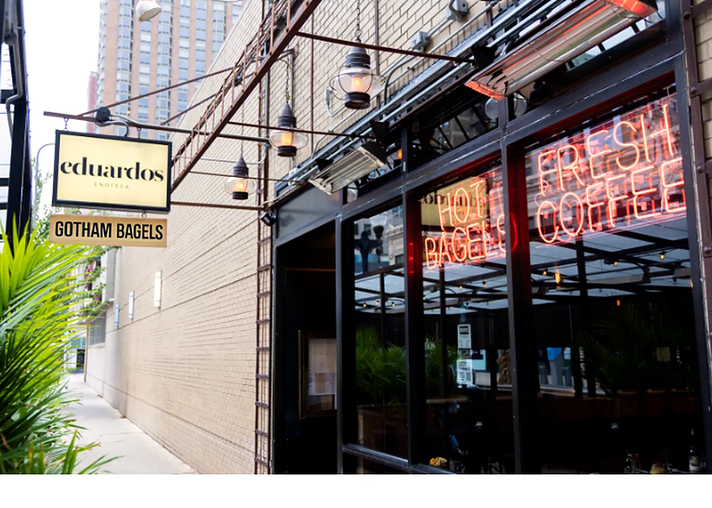 Gotham Bagels Gold Coast entrance under the Eduardo's Enoteca sign, with Hot Bagels and Fresh Coffee neon